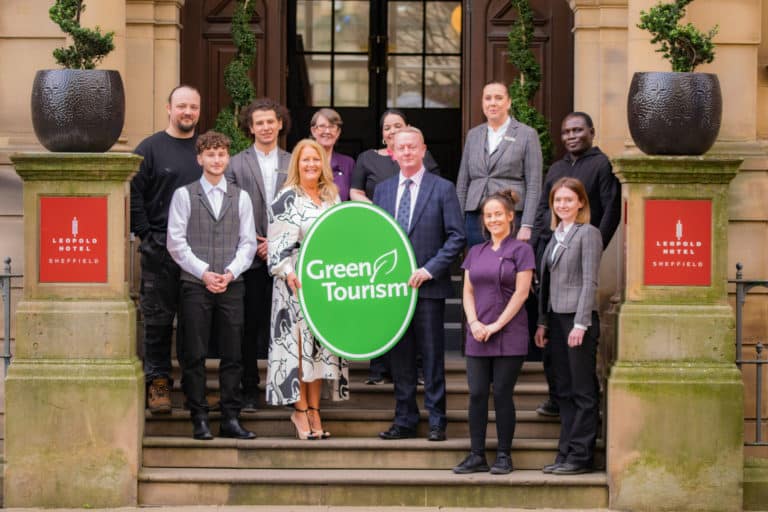 The team at Leopold Hotel Sheffield holding a Green Tourism sign on the steps of the Leopold Hotel.